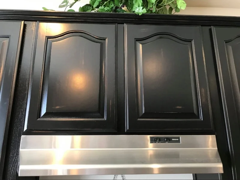 Black cabinets above a stainless steel hood