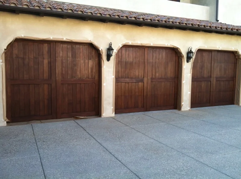 Three arched wooden garage doors on a stucco home